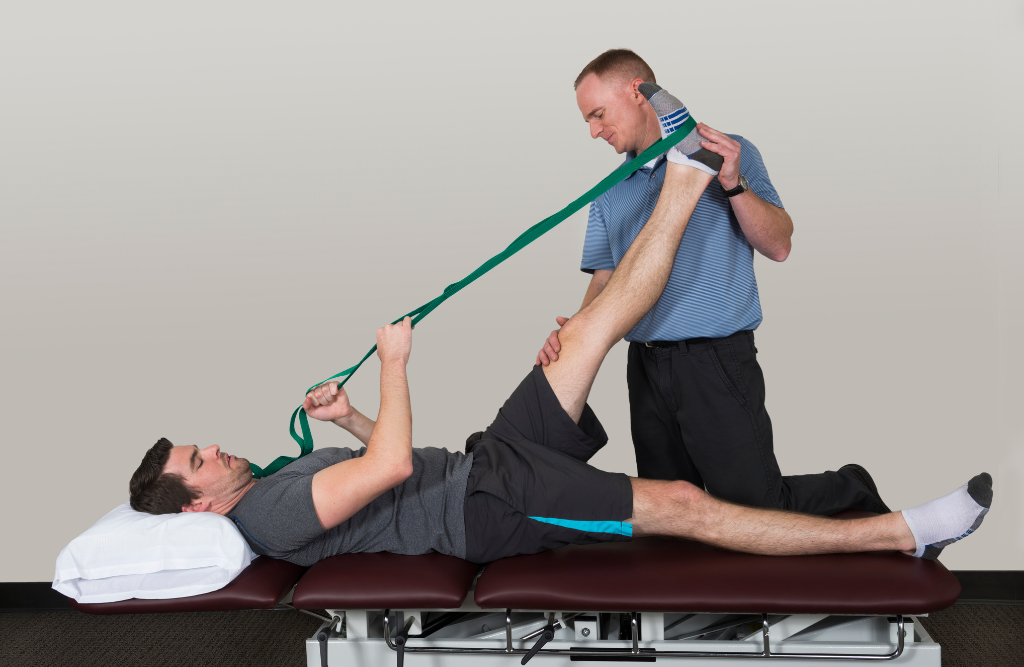 Physical therapist using a resistance band with client laying down