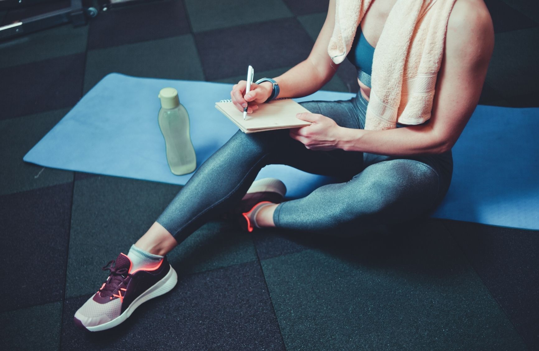 image of a personal trainer experiencing the benefits of being a personal trainer with a blue yoga mat and a green water bottle