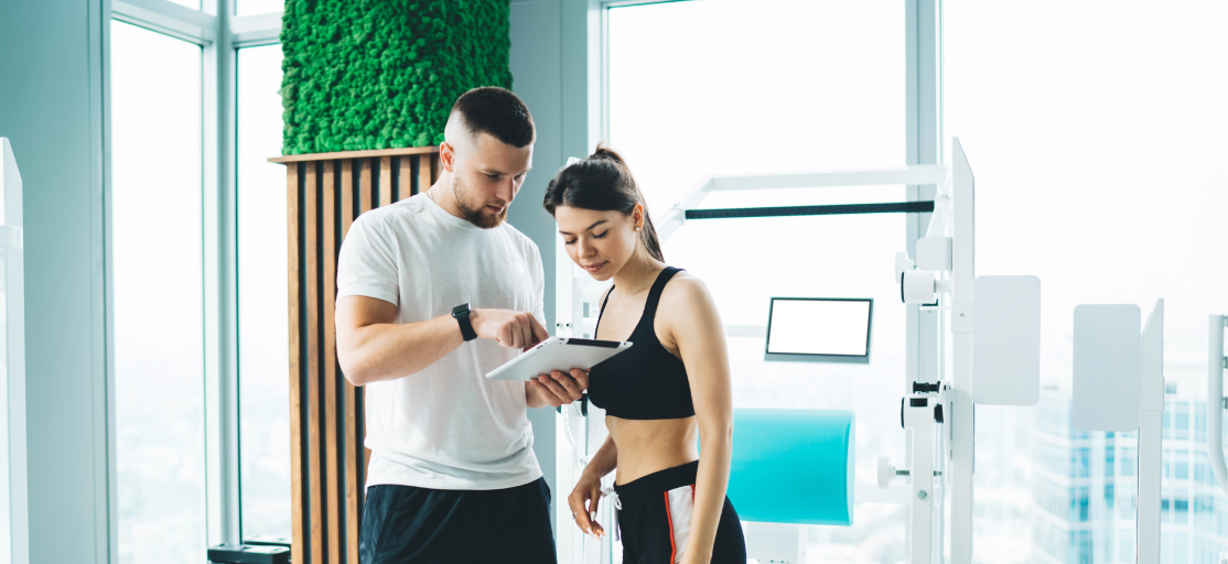 Image of a personal trainer showing a client the fastest way to build a client program in 2025